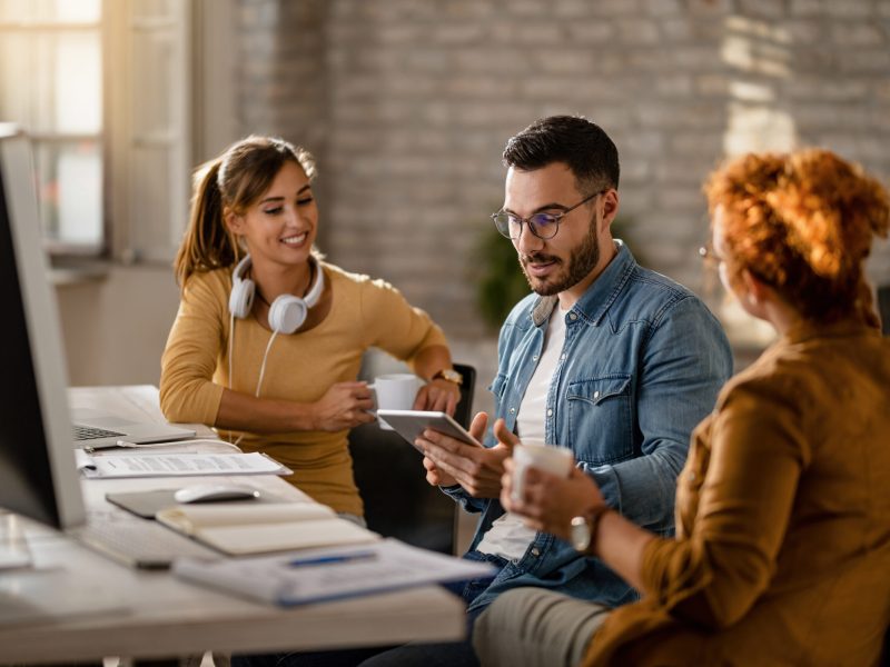 Team of young entrepreneurs having a business meeting in the office. Focus is on businessman using digital tablet.
